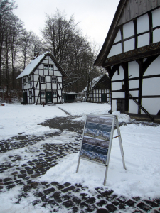 Ausstellungsplakat am verschneiten BauernhausMuseum Bielefeld